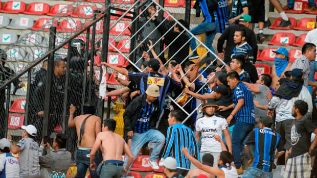 Fans clash during a Mexican soccer league match between the host Queretaro and Atlas from Guadalajara, at the Corregidora stadium, in Queretaro, Mexico, Saturday, March 5, 2022. Multiple people were injured during the brawl, including two critically. (AP Photo/Sergio Gonzalez)